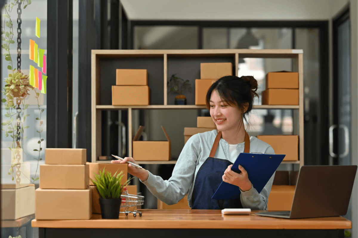 E-commerce business owner managing packages and orders with laptop
