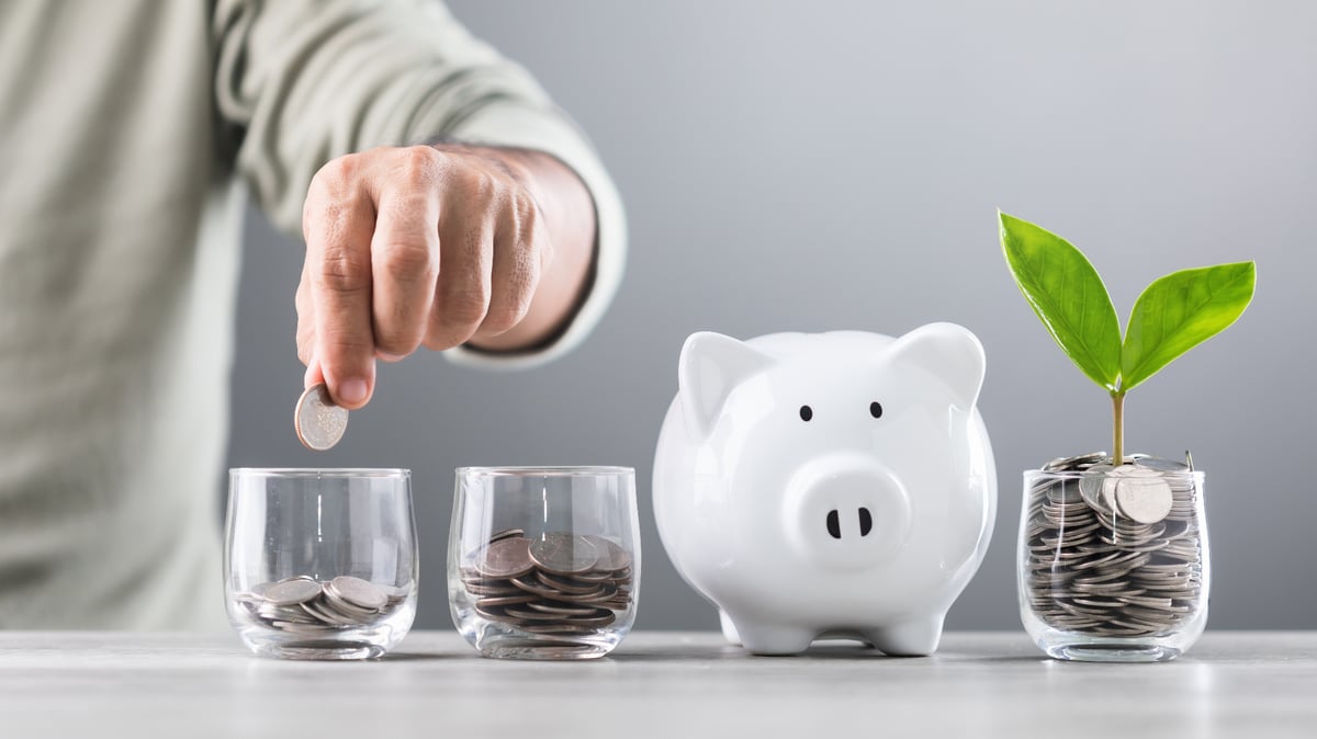 Person adding coins to glasses with a piggy bank and plant representing financial growth and savings