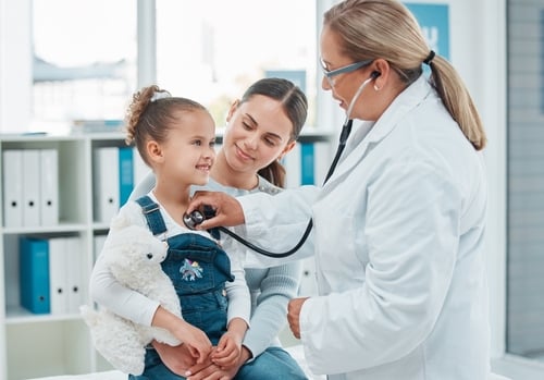 Pediatrician examining a child with mother present in a professional medical environment